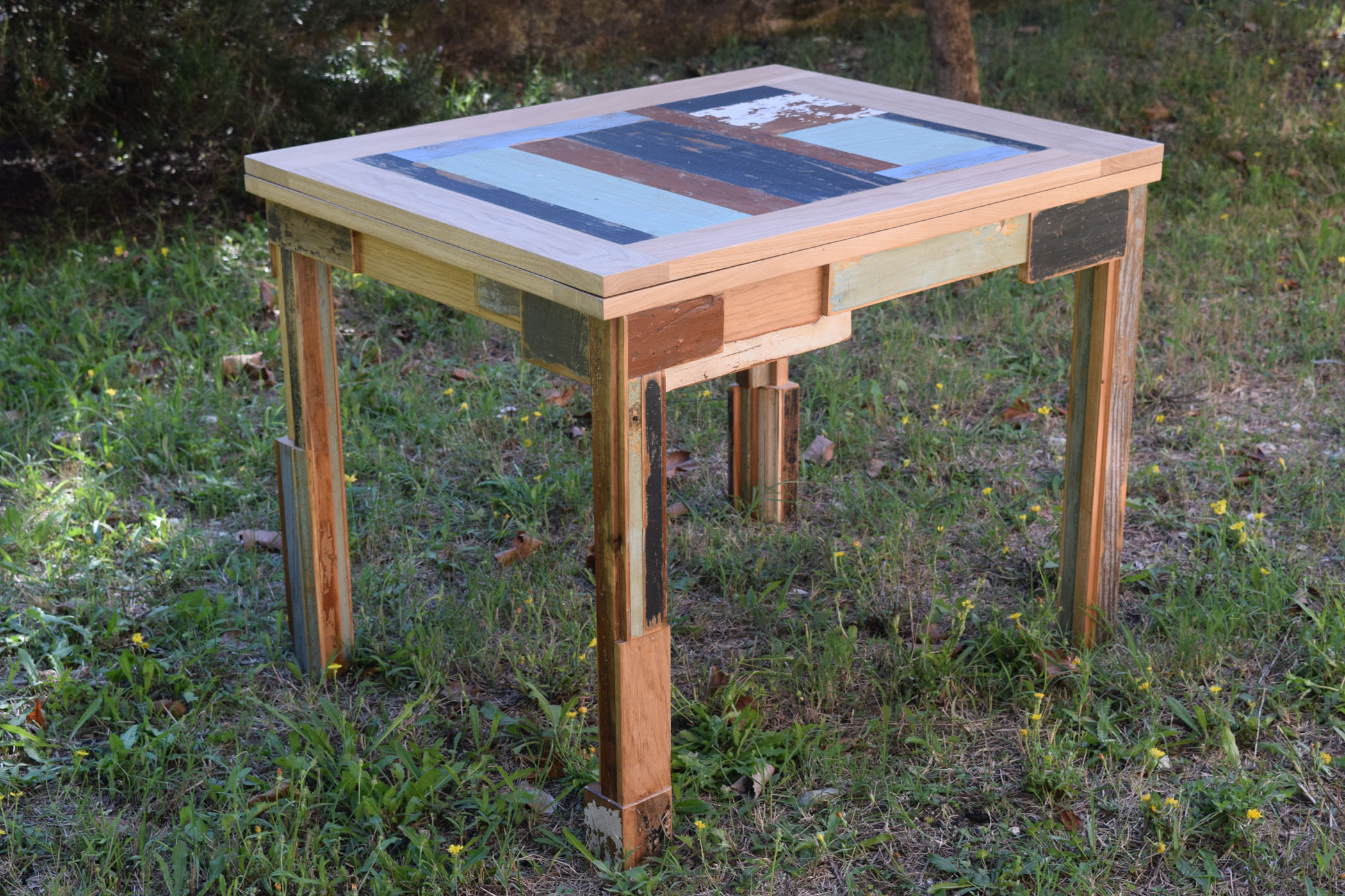 Tavolo allungabile interamente in legno di rovere massello con inserti di legno di recupero colorato. Piano del tavolo doppio e ribaltabile