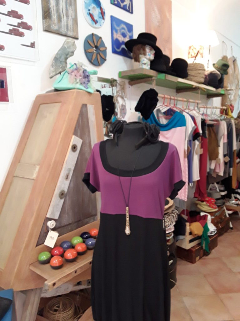 Vestito cucito a mano con manica corta viola e nero e mobile artigianale in legno massello e cassettini