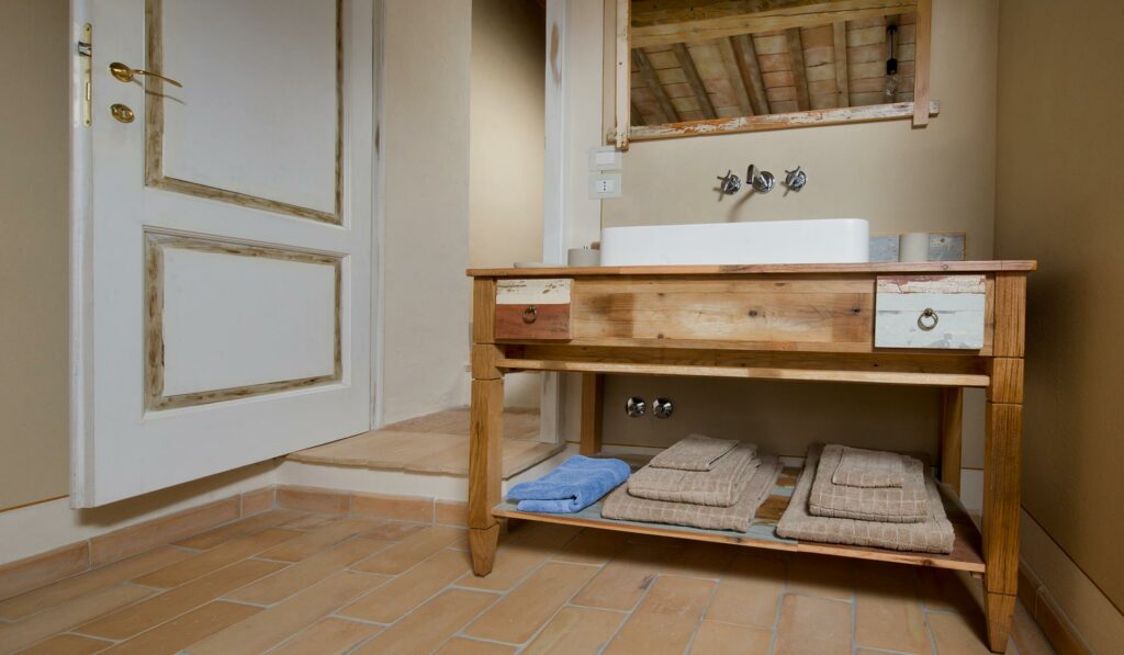 Immagine di uno dei mobili bagno in legno di recupero per un casale in Toscana con pavimento in cotto antico e pietra