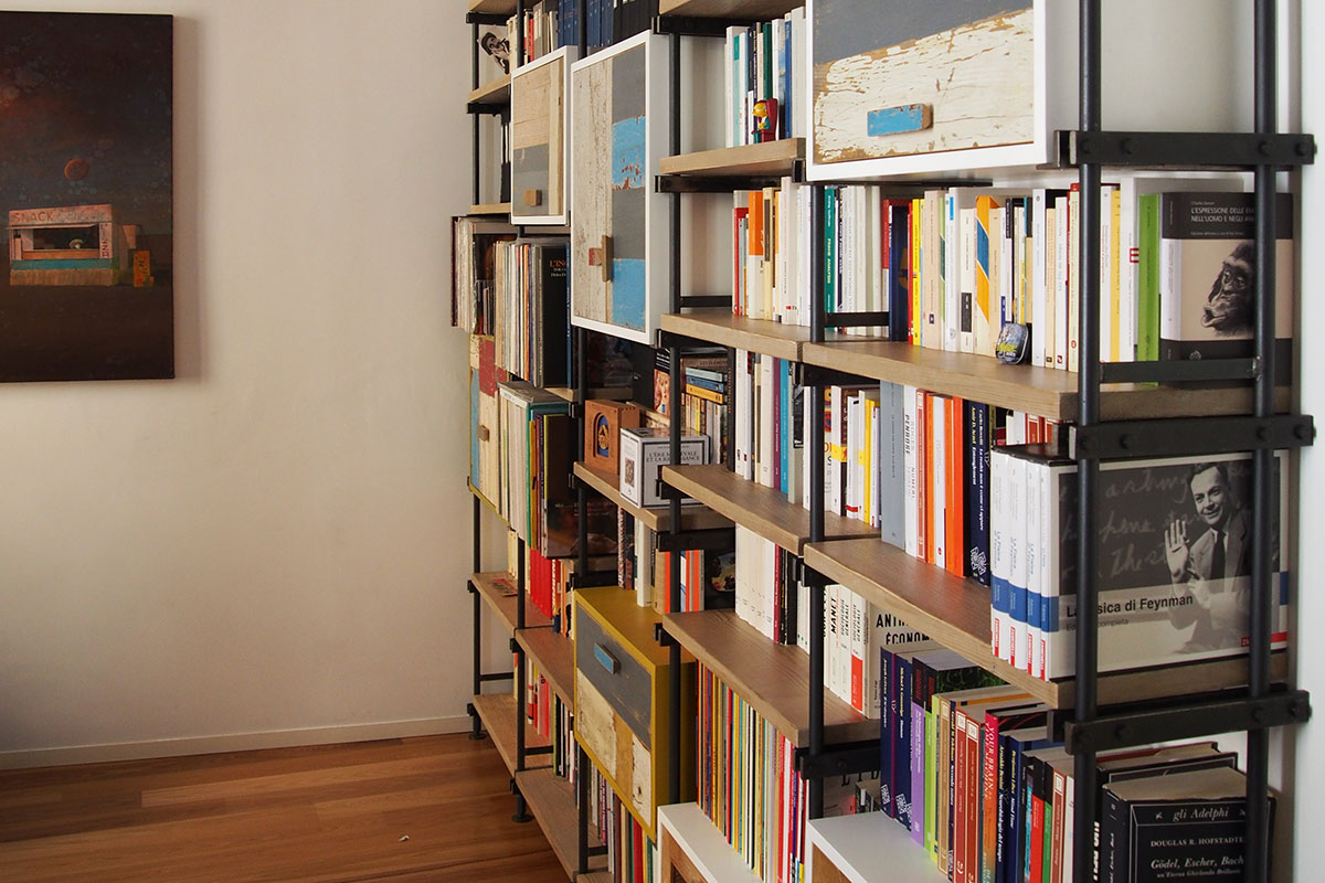 Vista laterale di una libreria con ripiani in legno massello e montanti in ferro scuro