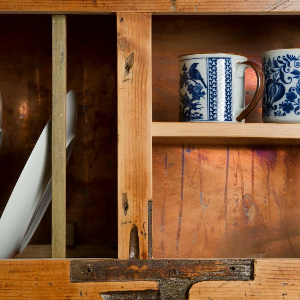 Primo piano del legno utilizzato per creare una piattaia in legno vintage per un casale in Toscana. Nela piattaia sono presenti ceramiche inglesi, tazze e piatti in porcellana antichi