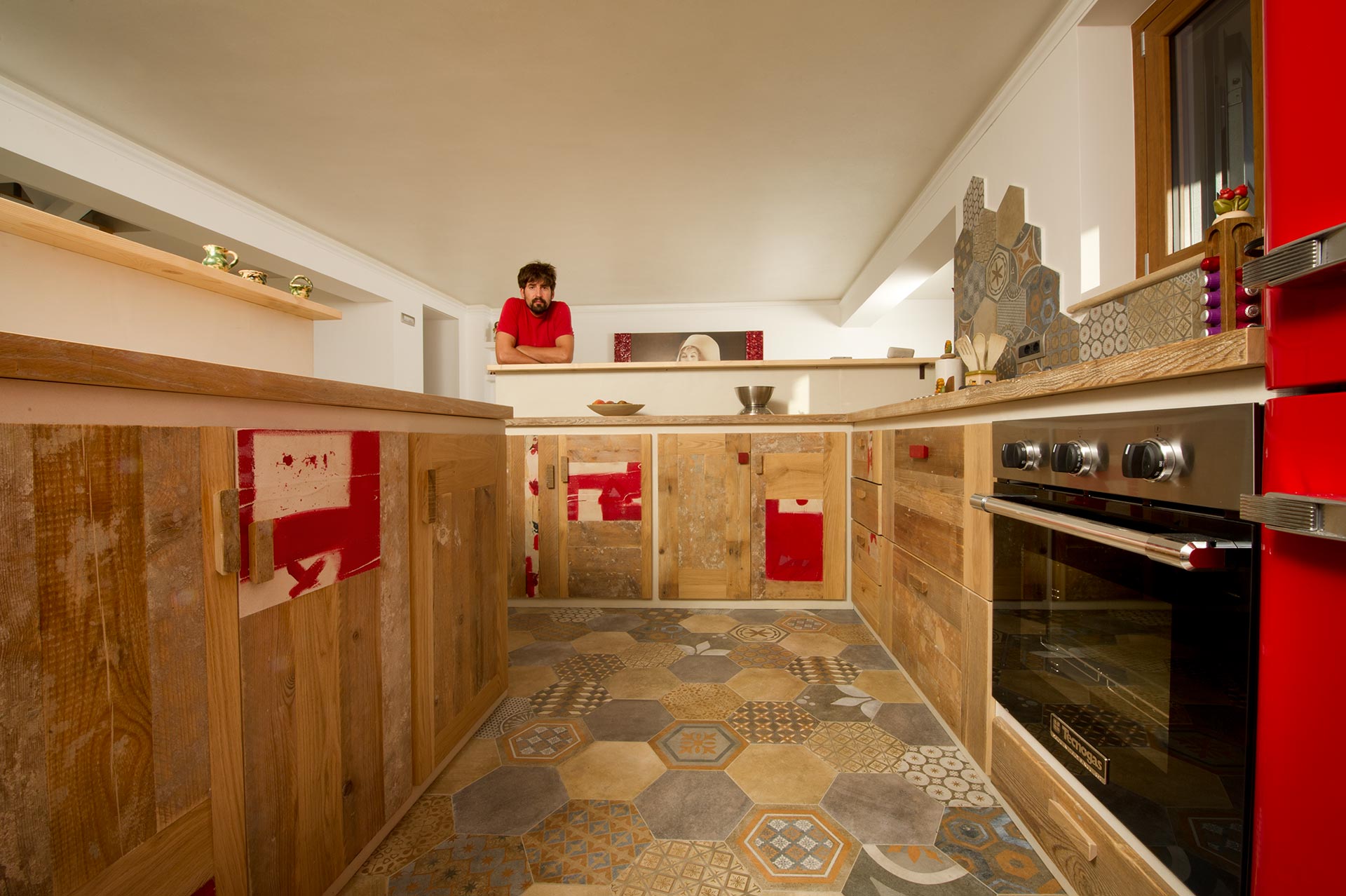 Vista totale di una cucina in legno su misura con dettagli di vernice e microcemento bianca e rossa. Al centro della foto Nicola Gubbiotti falegname e design dei mobili su misura Laquercia21